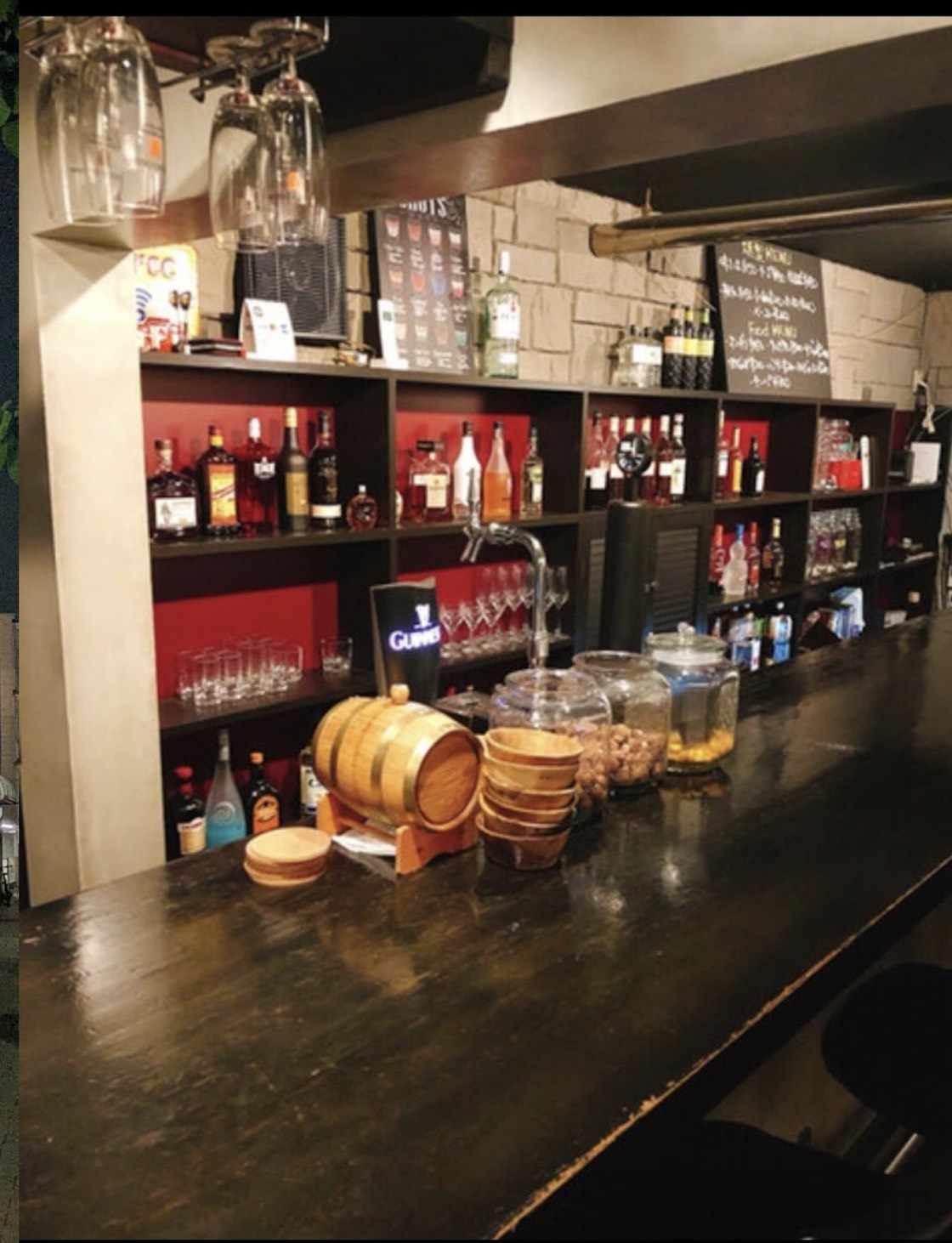 BAR REALTAの木のカウンターと、背後の酒棚や吊り下げられたグラス